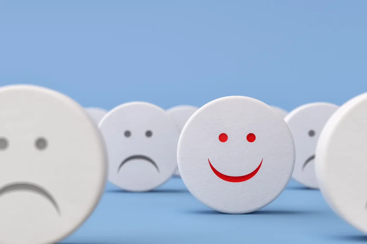 A happy smiling face among sad faces, representing customer satisfaction and trust.